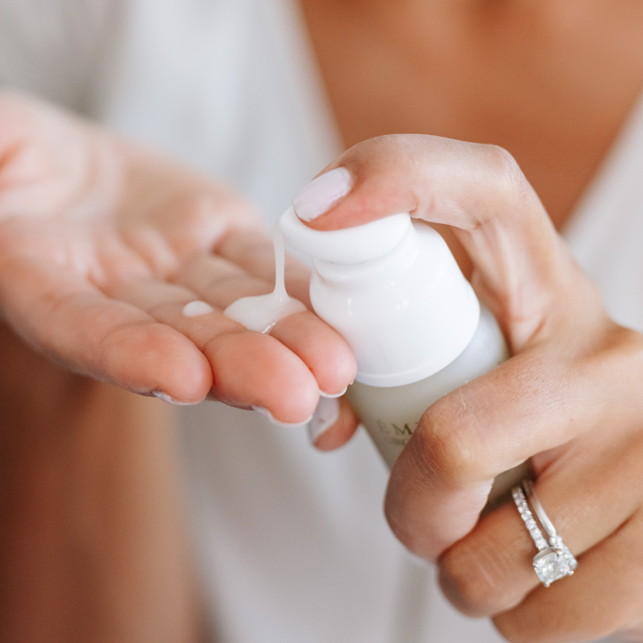 woman pumping Eminence Organics Acne Advanced Clarifying Hydrator into her hand