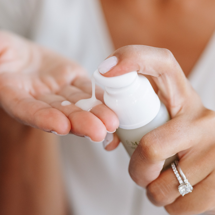 woman pumping Eminence Organics Acne Advanced Clarifying Hydrator into her hand