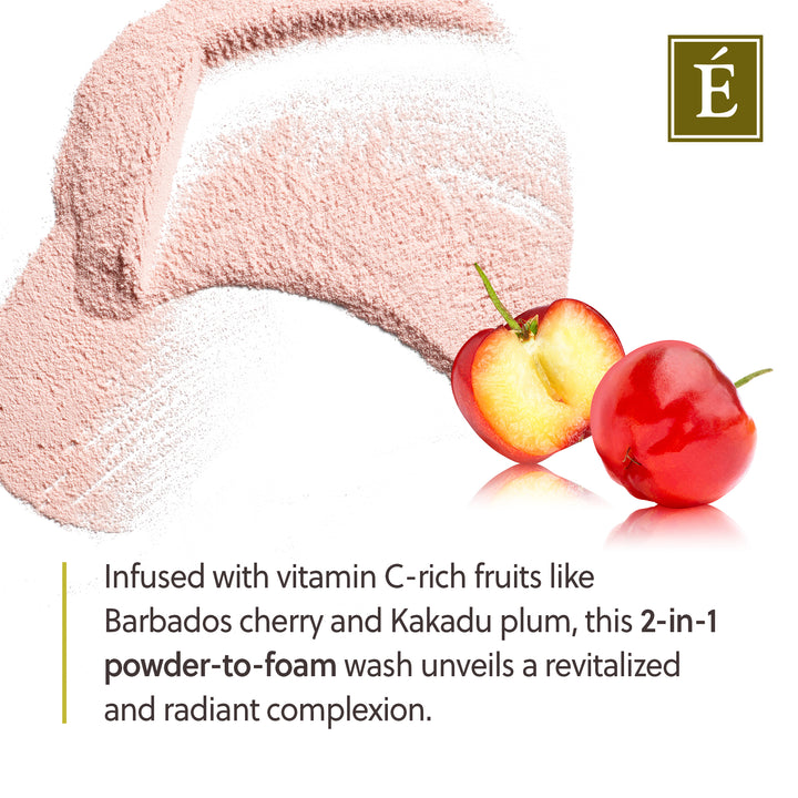 A close-up of pale pink powder with a white textured brush stroke on a white background, alongside two red cherries and a green brand logo in the top right. Text at the bottom describes a vitamin C-rich powder-to-foam wash inspired by Barbados cherry and Kakadu plum.
