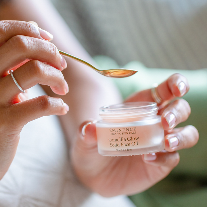 woman holding Eminence Organics Camellia Glow Solid Face Oil with a spoon