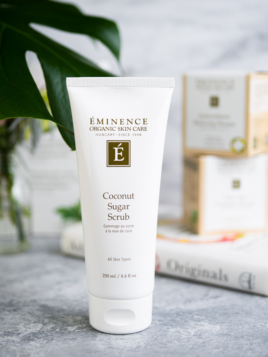 Tube of Eminence Coconut Sugar Scrub on a textured surface with a blurred background
