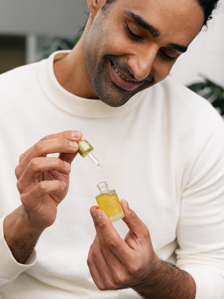 Man holding a dropper with Eminence Organics Facial Recovery Oil