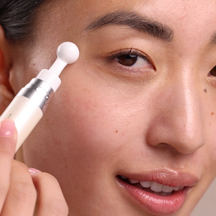Person applying Eminence Organics Hibiscus Ultra Lift Eye Cream to their face using a applicator.