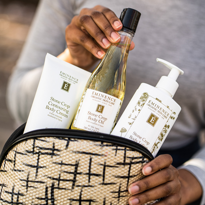 hand pulling Eminence Organics Stone Crop Body Oil from a bag