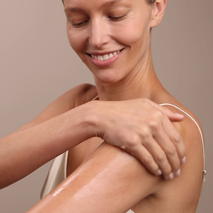 woman applying Eminence Organics Stone Crop Body Oil on her shoulder