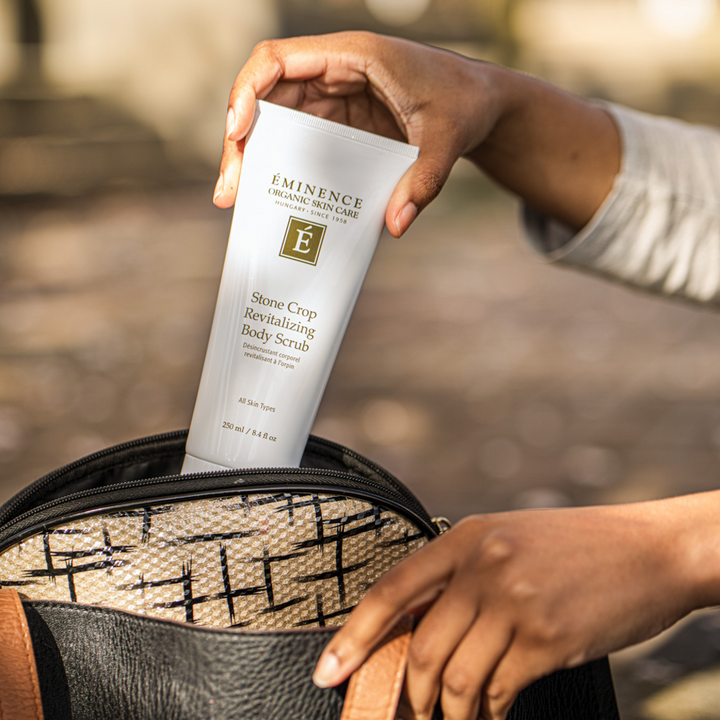woman pulling the Eminence Organics Stone Crop Revitalizing Body Scrub from her bag