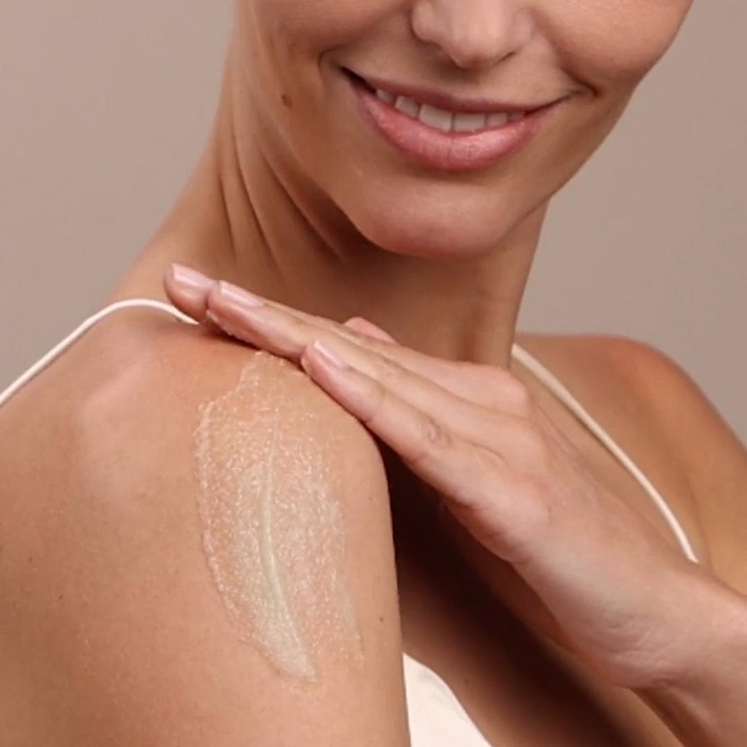 woman applying Eminence Organics Stone Crop Revitalizing Body Scrub to her shoulder