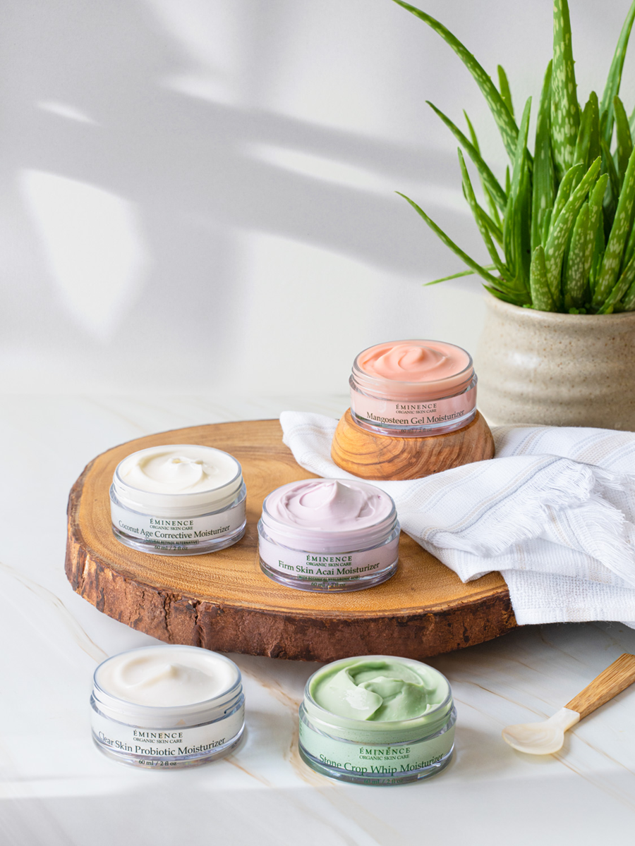 Collection of eminence organics jars on a wooden board with a plant in the background