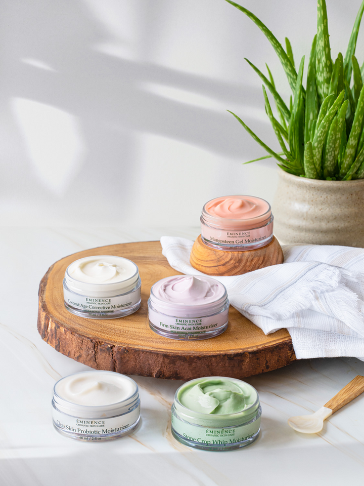 Collection of eminence organics jars on a wooden board with a plant in the background